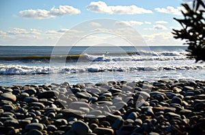 Waves breaking right with surfer cobblestone foreground bohkeh