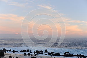 Waves breaking on the rocks of rugged Atlantic Ocean coast in Madeira Island, Portugal at sunrise