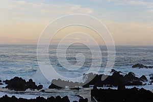 Waves breaking on the rocks of rugged Atlantic Ocean coast in Madeira Island, Portugal at sunrise