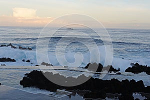 Waves breaking on the rocks of rugged Atlantic Ocean coast in Madeira Island, Portugal at sunrise