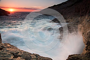 Waves breaking on a rocky seashore at sunset