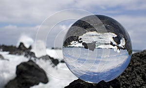Waves Breaking on Rough Lava Rock in Glass or Crystal Ball