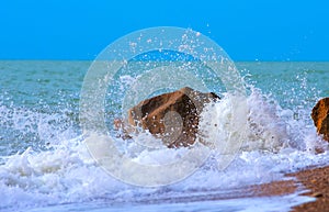 Waves breaking on the stone on the beach during a storm with blu