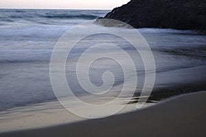 The waves calmly approach the shore of the beach, photo