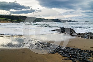 Waves on the coast in Verdicio beach in Asturias Spain. Choppy sea in a virgin beach with rocks and foam at evening