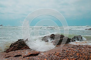 Waves crash against rocks on the shore in Legzira Beach. Rugged coastline in the Tiznit Province of Morocco, Africa. Rough