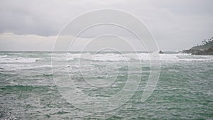 Waves crash against rocks at stormy sea. Spume sprays over stone breakwater. Weather change on coast brings rough surf