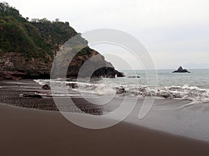 Waves crash on dark sand beach in Manzanillo, Mexico