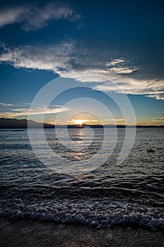 Waves crash on Lakeside Beach at Lake Tahoe during sunset with mountains splitting the middle of the picture