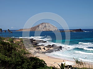 Waves crash on Makapuu Beach with Rabbit and Rock islands in the distance looking towards Waimanalo Bay