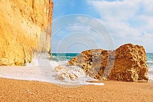 Waves crash on rocks on the sandy shores of benagil beach in portugal