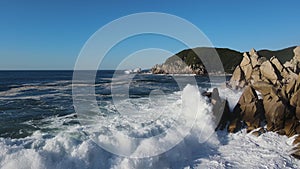 waves crashing against a rocky shoreline on a sunny day