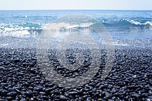 Waves crashing on a black pebble beach on the Big Island of Hawaii