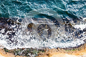 Waves crashing breaking on the rocks. Drone aerial sea surface view photo