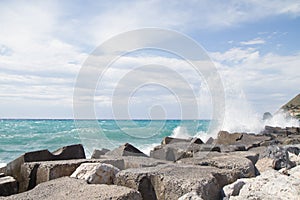 Waves crashing on the breakwater in front of a blue sky