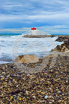 Waves crashing on on breakwater with lighthouse near the marina. Villeneuve-Loubet. France