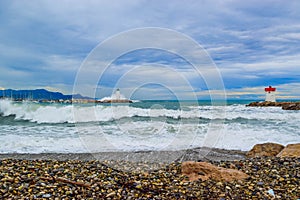 Waves crashing on breakwaters with two lighthouses near the marina. Villeneuve-Loubet. France