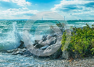 Waves crashing on Mackinac Island rocks with Mackinac Bridge in background