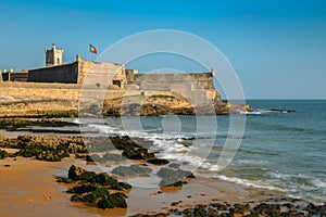 Waves crashing near the 16th Century Saint Julian Fortress at Carcavelos beach near Lisbon, Portugal