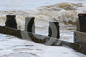 Waves crashing onto the weathered wooden groyne as the tide comes in