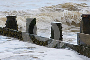 Waves crashing onto the weathered wooden groyne as the tide comes in photo