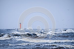 Waves crashing over a lighthouse, lighthouse in the sea in stormy day. Selective focus