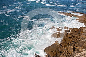 Waves crashing on rocks, Atlantic Ocean. Azure sea waves with white foam breaking on coast. Splash of aquamarine sea water.