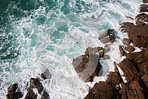 Waves crashing on rocks, Atlantic Ocean. Azure sea waves with white foam breaking on coast. Splash of aquamarine sea water.