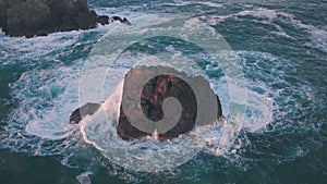 Waves crashing on rocks on Guernsey Coastline at sunset, Channel Islands, UK. Aerial drone