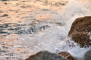 Waves crashing on the rocks at sunset.