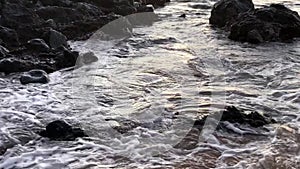 Waves crashing on rocks at sunset