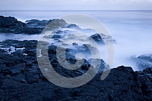 Waves crashing on rocky coast at dusk