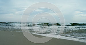 Waves crashing sand beach on grey cloudy weather. Aerial view ocean storming.