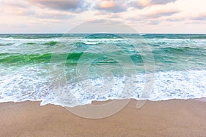 Waves crashing the sandy beach. clear horizon. changing windy weather