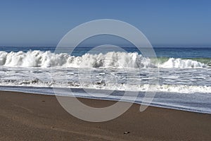 Waves crashing on a sandy beach making sea foam