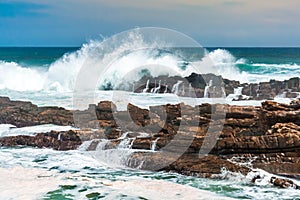 Waves crashing wildly on the rocky shore at Storms River Mouth, South Africa