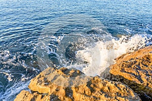 Waves crushing on the rocks on beach in the morning time. Sunrise on the wavy sea with rocks.