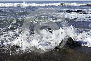 Waves crushing on a rocky beach making sea foam on Moonstone Beach