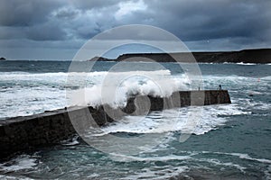 Waves engulf the the harbour wall at Sennen Cove Cornwall UK 