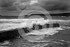 Waves engulf the the harbour wall at Sennen Cove Cornwall UK - black and white