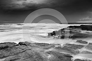 Waves engulf the rock shelf as moody weather increases swells photo