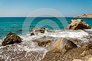 Waves entering Pissouri pebble beach through large rocks in the water, Cyprus