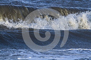 Waves with foam heads hit the coast of Goeree Overflakkee