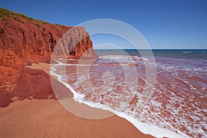 Waves at high tides breaking against the red pindan cliffs at James Price Point, Western Australia