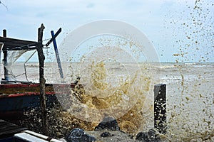 Waves hit fishing boats as they moored on the beach in monsoon season