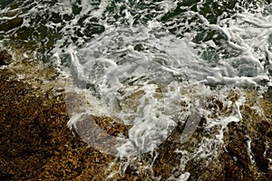 Waves hit rocks at shore Greek island of Kalymnos summer sun water