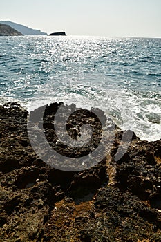 Waves hit rocks at shore Greek island of Kalymnos summer sun water