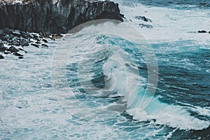 Waves hitting coastling - black cliff on ocean coast -
