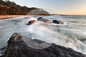 waves hitting rocks in the morning light at beach on nsw south coast of australia