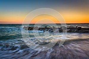 Waves and a jetty at sunset in the Atlantic Ocean at Edisto Beach, South Carolina.